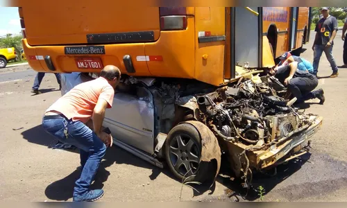 Carro fica embaixo de ônibus após grave acidente