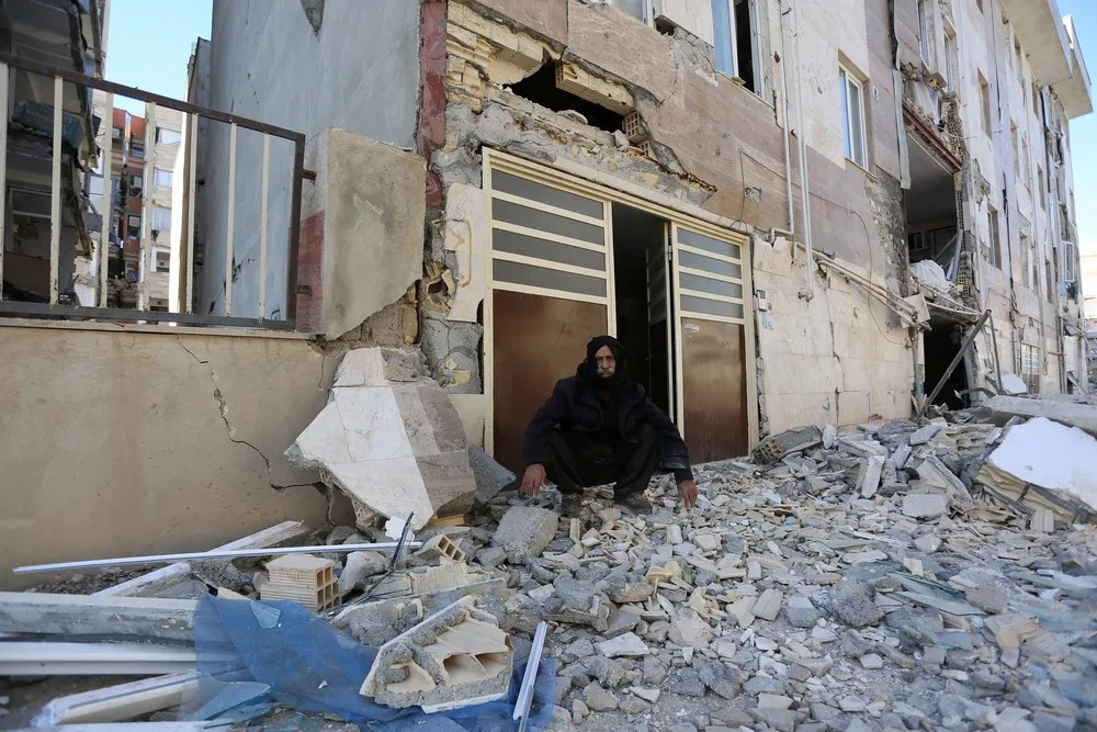 Homem é fotografado sentado sobre destroços, nesta segunda-feira (13), após tremor que atingiu a província iraniana de Kermanshah (Foto: Tasnim News Agency/ Reuters)