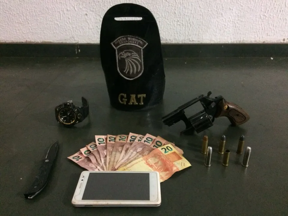 Dinheiro, celular, relógio roubados e a arma usada no assalto. Foto: Divulgação/GM