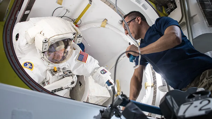 O astronauta Joe Acaba auxilia o colega Scott Tingle durante uma verificação de ajuste em seu traje espacial: fezes poderão ser transformadas em comida no espaço- Foto: NASA