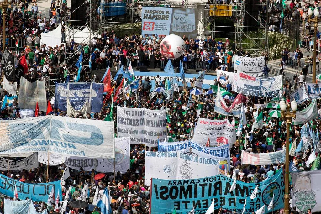 Grupo de manifestantes é visto de cima. Eles carregam faixas de pano. Milhares de membros de centrais sindicais participam de protesto na praça de Maio, em Buenos Aires, prévio à greve geral desta terça-feira (25) - Foto: Damian Dopacio/Noticias Argentinas/AFP