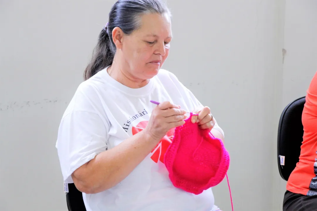 Voluntárias criam toucas para doação às pacientes em tratamento contra o câncer.