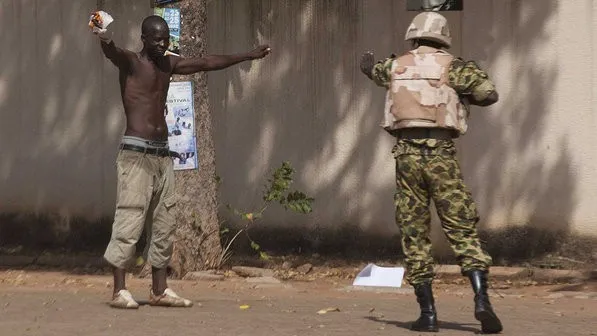 Manifestante anti-governo enfrenta um soldado das Forças Nacionais, do lado de fora do edifício do parlamento em Uagadugu, capital de Burkina Fasso - (Joe Penney/Reuters)