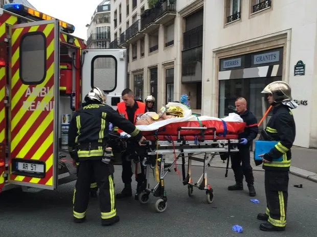 Pessoa ferida na sede da revista satírica Charlie Hebdo, em Paris, é socorrida após ataque a tiros deixar mais de 10 mortos e vários feridos (Foto: Philippe Dupeyrat/AFP)