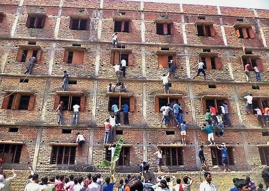 Indianos escalam prédio em que estudantes fazem uma prova em Hajipur, no leste do estado de Bihar - Foto: Press Trust of India / AP
