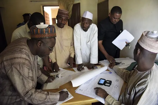 Oficiais da comissão eleitoral independente da Nigéria coletam dados da eleição deste sábado (28) enquanto eleitores continuavam a votar neste domingo (29) (Foto: Pius Utomi Ekpei/AFP)