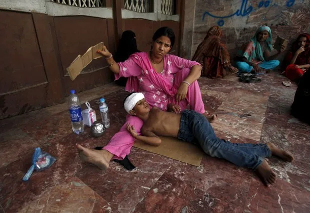 Mulher abana filho do lado de fora de hospital em Karachi, no Paquistão, nesta terça-feira (23), em meio a onda de calor que já matou centenas de pessoas no país (Foto: Akhtar Soomro/Reuters)