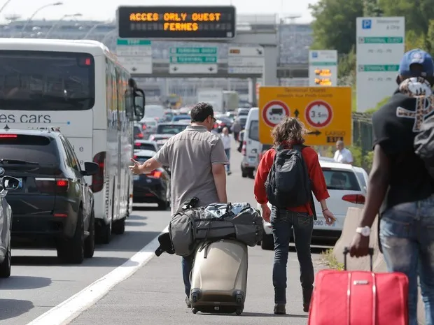 Passageiros arrastam suas malas para o aeroporto de Orly, em Paris. Taxistas em greve bloqueiam as ruas de acesso à aerportos e estações de trem de Paris e outras cidades durante um protesto nacional contra o serviço de compartilhamento de carro Uber (Foto: Christian Hartmann/Reuters)