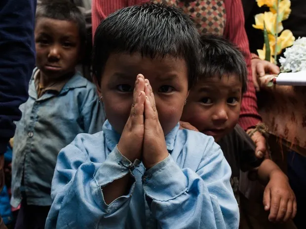 Menino nepalês faz saudação 'namastê', reverência típica (Foto: Rafael Saes/Divulgação)