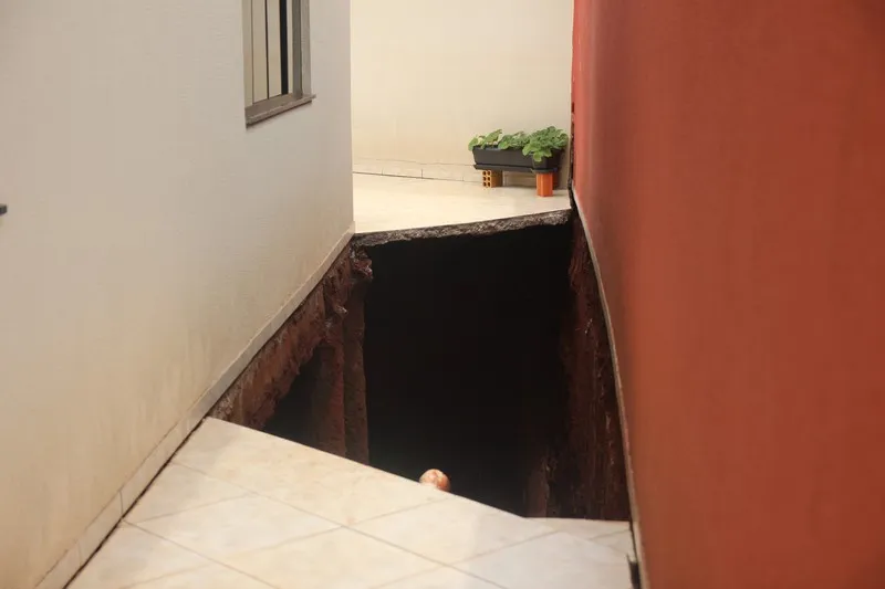 Uma cratera se abriu ao lado e sob o muro de casa na Rua Bandeirantes: interdição por risco de desabamento - Foto: José Luiz Mendes