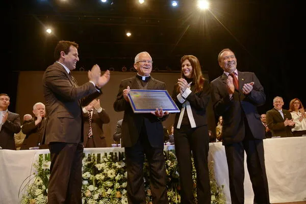 Padre Carrara recebe homenagem das mãos dos autores do projeto de lei (Foto: Sérgio Rodrigo)